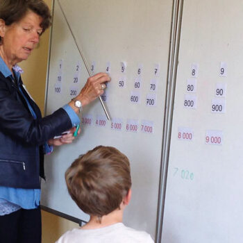 Enseignant avec élève au tableau pour leçon de mathématiques