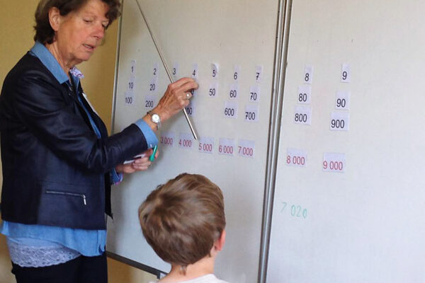 Enseignant avec élève au tableau pour leçon de mathématiques