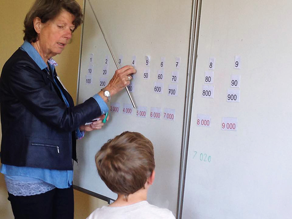 Enseignant avec élève au tableau pour leçon de mathématiques